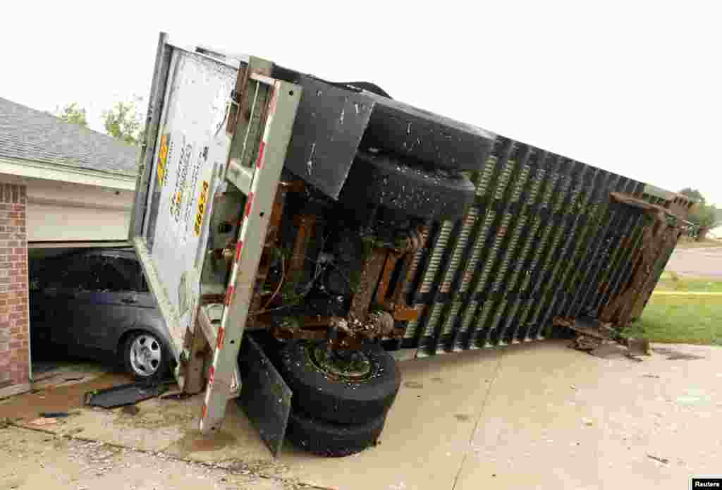 A trailer blown into a home on Lindsay Lane in Cleburne rests on a car after a tornado in Cleburne, Texas May 16, 2013.