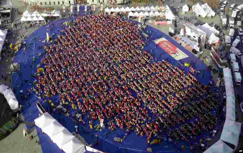 Người tham gia xếp thành hình trái tim trong khi làm món kim chi truyền thống của Hàn Quốc, trước Tòa thị chính Seoul, Hàn Quốc, trong một nỗ lực lập kỷ lục thế giới Guinness cho món kim chi được nhiều người làm nhất tại cùng một nơi.