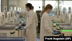 Research assistants watch the sequencing machines analyzing the genetic material of COVID-19 cases at the Wellcome Sanger Institute, Genome Campus, Hinxton, Cambridgeshire, England, Friday, on Jan. 7, 2022. (AP Photo/Frank Augstein)