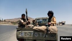 FILE - Houthi fighters ride on the back of a pickup truck on a road between the port city of Hodeida and capital Sanaa, Yemen, April 19, 2017.