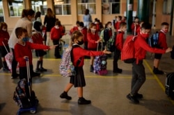 Sekelompok siswa muda yang mengenakan masker sedang mengantri dan menerapkan jarak sosial sebelum memasuki ruang kelas, di sekolah Luis Amigo, di Pamplona, Spanyol utara, 7 September 2020. (Foto: AP)