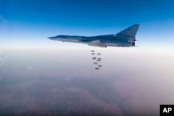FILE- In this frame grab from video provided by the Russian Defense Ministry Press Service, a Russian Tu-22M3 bomber flies during a strike above an undisclosed location in Syria on Aug. 14, 2015.