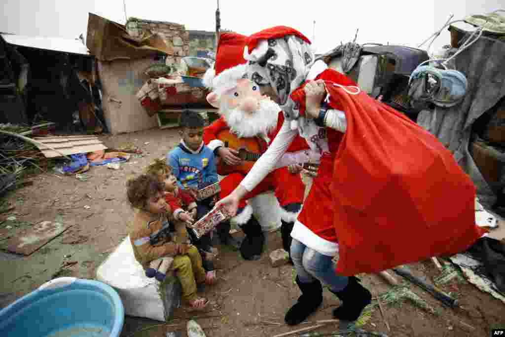 An Iraqi student dressed in a Santa Claus outfit distribute gifts to impoverished children outside their shanty home in the Shi&#39;ite city of Najaf.