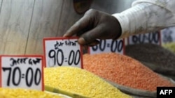Người bán hàng sắp xếp thẻ giá các loại ngũ cốc tại một khu chợ ở New Delhi
