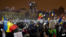 Protesters lit torches and wave flags as they gather outside the government building in Bucharest, Romania, Feb. 11, 2017. 