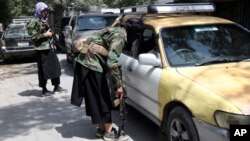 In this Aug. 22, 2021, file photo, Taliban fighters search a vehicle at a checkpoint on the road in the Wazir Akbar Khan neighborhood in the city of Kabul, Afghanistan. (AP Photo/Rahmat Gul, File)
