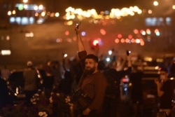 FILE - A man holds up a phone with its flashlight on during a rally of opposition supporters, who accuse Belarusian President Alexander Lukashenko of rigging the polls in his favor, in Minsk, Belarus, Aug. 10, 2020.