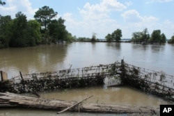 FILE - In this Aug. 31, 2017, photo, a barbed-wire fence encircles the Highlands Acid Pit that was flooded by water from the nearby San Jacinto River as a result from Harvey in Highlands, Texas.