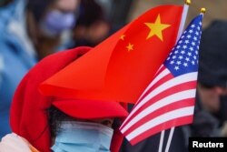 Seseorang memegang bendera AS dan China saat perayaan Tahun Baru Imlek Kota New York ke-22, di kawasan Pecinan di wilayah Manhattan di Kota New York, New York, AS, 12 Februari, 2021. (Foto: REUTERS/Carlo Allegri)