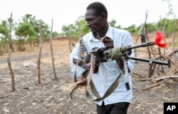 An opposition fighter walks with his weapon on which is tied a red ribbon, signifying danger as a warning to government forces and a willingness to shed blood, according to an opposition spokesman, in Akobo town, one of the last rebel-held strongholds in