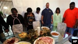 Rondy Bridges, third from right, leads a Thanksgiving Day prayer before he and members of his family have their holiday meal. (file)