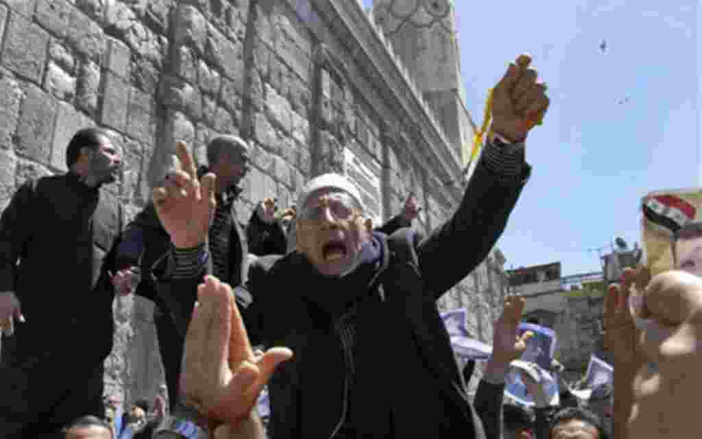 A Syrian pro-government protester shouts slogans during a protest following Friday prayers outside the Omayyad Mosque in Damascus, Syria, April 15, 2011