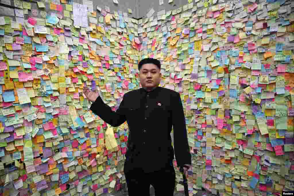 Howard, a 35-year-old Australian Chinese musician and lookalike of North Korean leader Kim Jong Un, gestures in front of a wall with messages of support to pro-democracy protesters in part of Hong Kong's financial central district they are occupying.