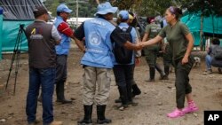 FILE - A United Nation observer shakes hands with a rebel of Revolutionary Armed Forces of Colombia (FARC) before a meeting in La Carmelita near Puerto Asis in Colombia's southwestern state of Putumayo, March 1, 2017. Thousands of leftist rebels are taking an important step in Colombia’s peace process by providing to UN observers an inventory of the weaponry they will soon surrender.