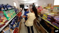 FILE - In this Aug. 23, 2019, photo, immigrants seeking asylum shop in a small store at the ICE South Texas Family Residential Center in Dilley, Texas. The isolation of at least three families at the center at that time raised fears of the coronavirus spreading through the facility.