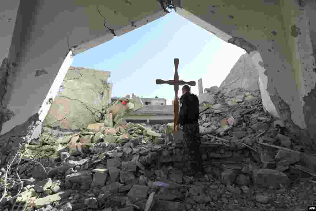 A member of the Syrian Arab-Kurdish forces places a cross in the rubble ahead of a Christmas celebration at the heavily-damaged Armenian Catholic Church of the Martyrs in the city centre of the eastern Syrian city of Raqqa.