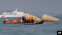 South Korean rescue team members on a boat approach to the buoys which were installed to mark the area of the sunken ferry Sewol in the water off the southern coast near Jindo, south of Seoul, South Korea, Sunday, April 20, 2014.