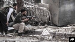 Syrian rebel fighters take cover as a Syrian army sniper aims over a destroyed mosque in Tarik Al-Bab, southeast of Aleppo, October 26, 2012.