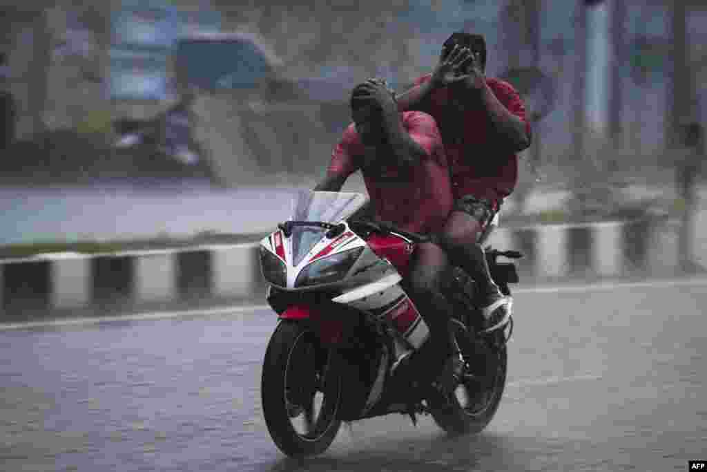 Motorist ride along a road during a heavy rainfall in Chennai, India.