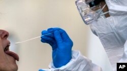 In this Wednesday, April 1, 2020 filer, medical staff of a mobile unit take samples from a woman to test for Covid-19, at the Santa Maria della Pieta' hospital complex, in Rome. (Cecilia Fabiano/LaPresse via AP, File)