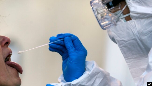 In this Wednesday, April 1, 2020 filer, medical staff of a mobile unit take samples from a woman to test for Covid-19, at the Santa Maria della Pieta' hospital complex, in Rome. (Cecilia Fabiano/LaPresse via AP, File)