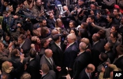 FILE - Then-Republican presidential candidate Donald Trump, center right, says goodbye to Dr. Darrell Scott, foreground left center, the senior pastor of New Spirit Revival Ministries in Cleveland Heights, Ohio, surrounded by media in the lobby of Trump Tower in New York, after meeting a coalition of 100 African-American evangelical pastors and religious leaders, Nov. 30, 2015.