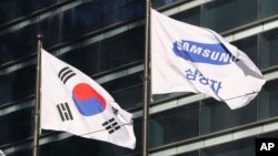 The company flag of Samsung Electronics (R) flutters next to the South Korean national flag in Seoul, South Korea, Jan. 16, 2017
