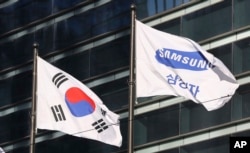 The company flag of Samsung Electronics (R) flutters next to the South Korean national flag in Seoul, South Korea, Jan. 16, 2017