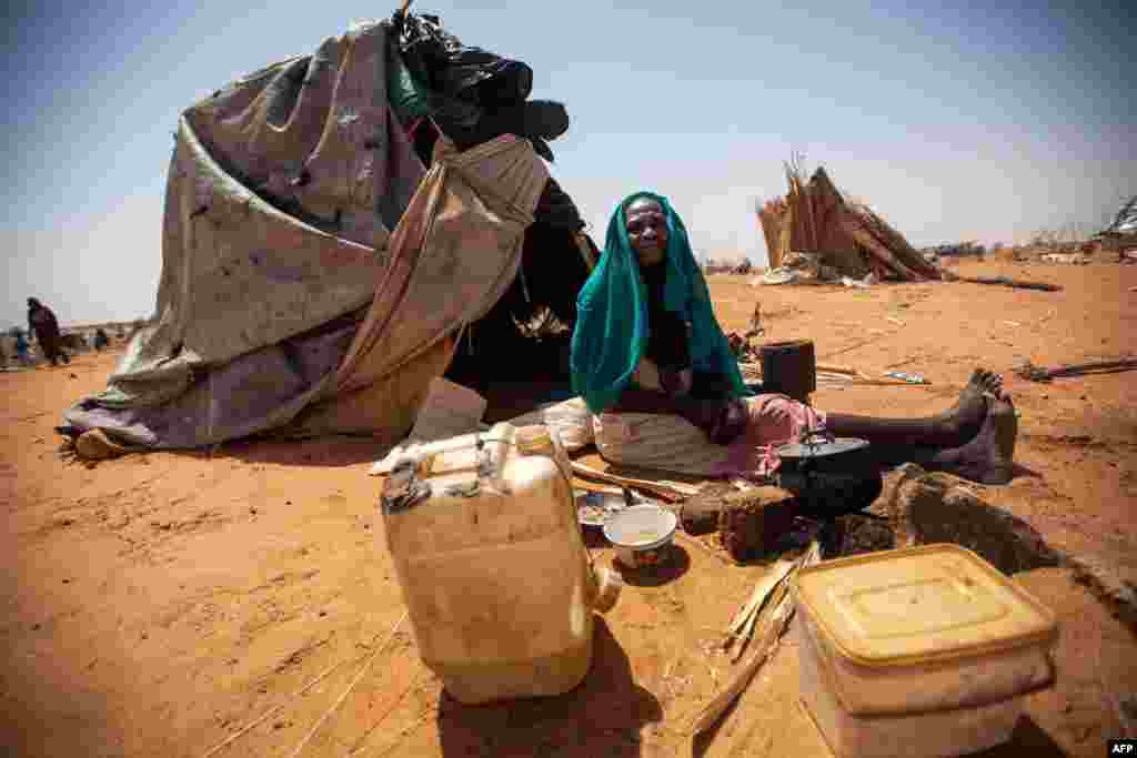 A handout picture released by the United Nations-African Union Mission in Darfur (UNAMID) shows Aisha Abdala, a displaced woman from Katila, South Darfur, cooking next to her shelter at the al-Sereif camp for Internally Displaced Persons (IDP) in Nyala, South Darfur, Sudan.