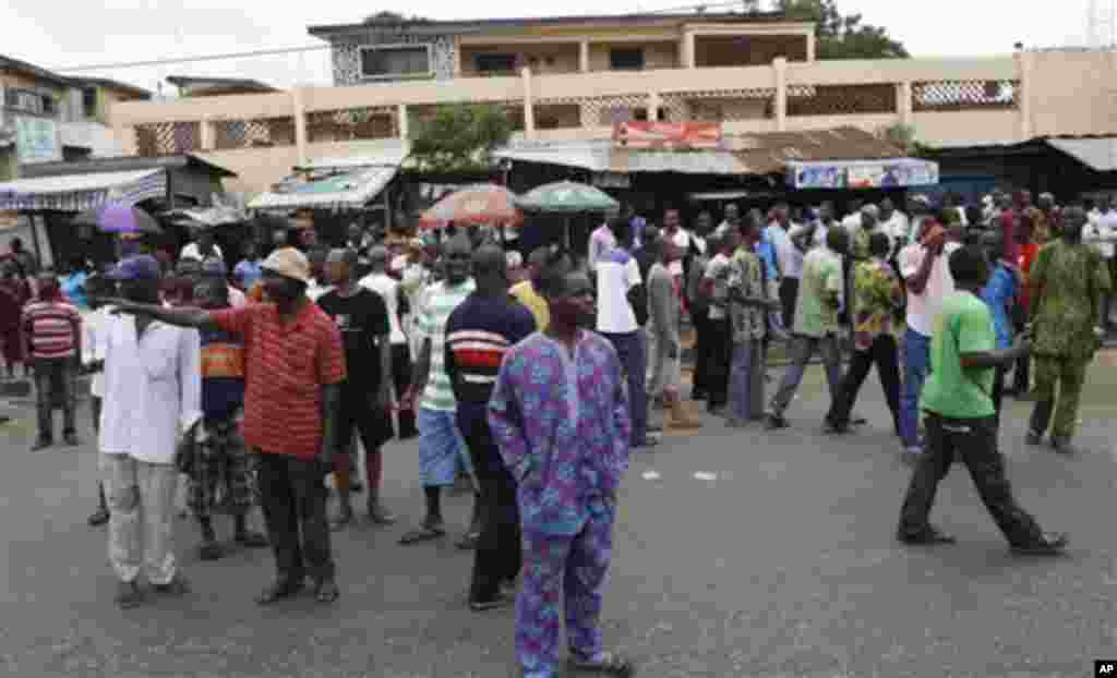 People wait outside a polling station in Ibadan, Nigeria, Saturday, April 2, 2011, as the election is postponed. Nigeria postponed its National Assembly elections Saturday as ballots and tally sheets remained missing from polling places throughout the na