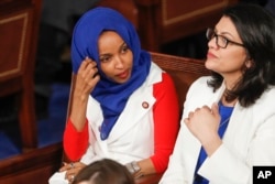 FILE - Rep. Ilhan Omar, D-Minn., left, joined at right by Rep. Rashida Tlaib, D-Mich., listens to President Donald Trump's State of the Union speech, at the Capitol in Washington.