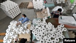 Công nhân đang làm việc trên dây chuyền dệt vải cotton ở Tân Cương Xinjiang
