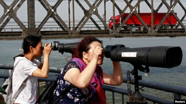 中国游客在辽宁省丹东市跨越鸭绿江的友谊桥边通过望远镜遥望朝鲜。(2018年5月24日)