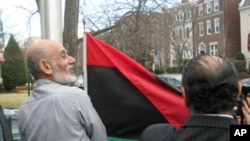 Activists raise the Libyan independence flag outside the Libyan ambassador's home in Washington, D.C., February 25, 2011