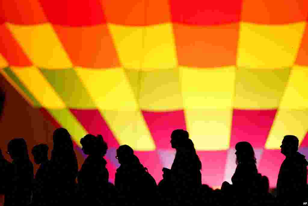 People are silhouetted against a hot air balloon on the grounds of the National World War I Museum and Memorial, May 30, 2021, in Kansas City, Missouri.