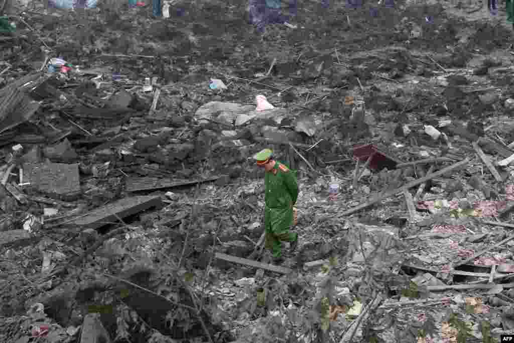 A policeman walks across debris after a big explosion razed five homes and shattered windows of surrounding buildings in the northern province of Bac Ninh.
