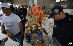 FILE - Venezuelan volunteers, Colombian firefighters and rescue workers prepare USAID humanitarian aid for storage at a warehouse next to the Tienditas International Bridge, near Cucuta, Colombia, on the border with Venezuela, Feb. 8, 2019.