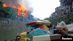 Residents watch from a distance as houses are engulfed in fire in Quezon city, metro Manila, Philippines, Jan. 1, 2015. (Reuters)