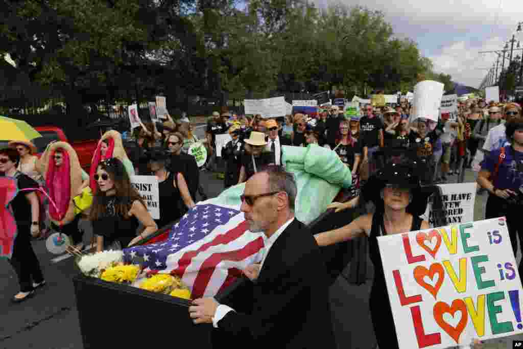 Protesters walk beside The Statue of Liberty in a coffin during a mock second line jazz funeral procession down the streets of New Orleans in protest of the inauguration of Donald Trump, Jan. 20, 2017. 