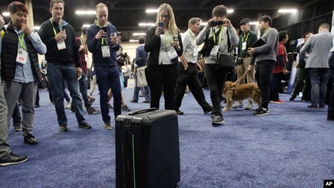 Attendees take pictures of ForwardX Robotics' CX-1 self-driving luggage during CES Unveiled at CES International Sunday, Jan. 7, 2018, in Las Vegas. (AP Photo/Jae C. Hong)