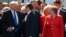 FILE - German Chancellor Angela Merkel, right, watches as U.S. President Donald Trump, left, shakes hands with French President Emmanuel Macron, center, during a ceremony at NATO headquarters in Brussels, May 25, 2017. 