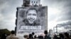 People attend the installation of a tarp depicting jailed Algerian journalist Khaled Drareni by French street artist and painter Christian Guemy, aka C215, in Paris, Oct. 15, 2020.