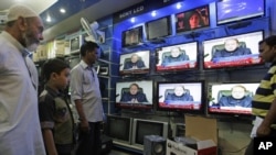 People watch Prime Minister of Pakistan Nawaz Sharif addressing the nation, at an electronic shop in Karachi, Aug. 19, 2013. 