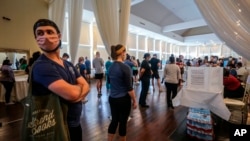 Voters wait in line to cast their ballots in the state's primary election at a polling place, Tuesday, June 9, 2020, in Atlanta, Ga. Some voting machines went dark and voters were left standing in long lines in humid weather as the waiting game…