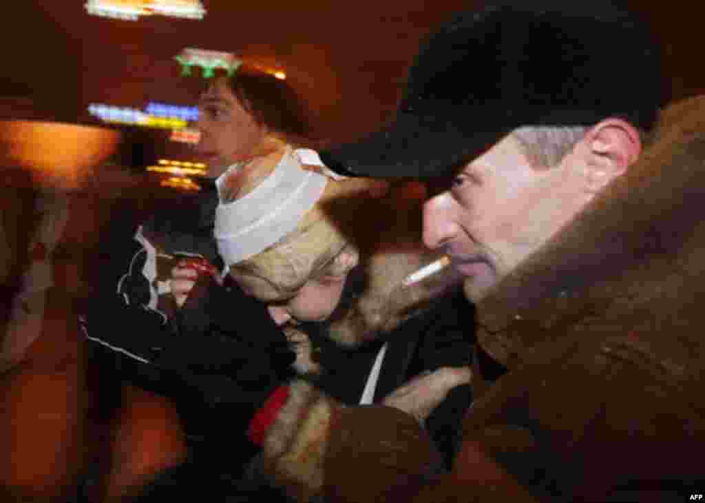 An activist helps a young woman injured in clashes between riot police and demonstrators trying to storm the government building in the Belarusian capital, Minsk, Sunday, Dec. 19, 2010. Thousands of opposition supporters in Belarus tried to storm the main