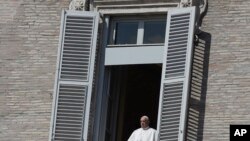 Pope Francis leans out of his studio window overlooking St. Peter's Square at the Vatican, March 15, 2020. 