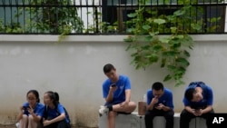 资料照：2023年8月3日，星期四，北京街头，年轻人看着他们的智能手机。