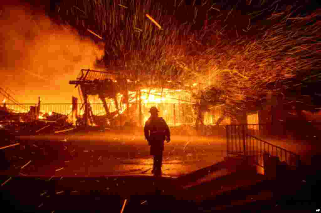 Un bombero examina una casa en llamas mientras el incendio de Hillside arde en San Bernardino.