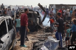 Warga Palestina berkumpul di lokasi serangan udara Israel terhadap tenda-tenda di kamp pengungsi internal di Rafah pada 27 Mei 2024 yang menewaskan sedikitnya 45 orang.