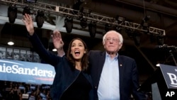 Democratic presidential candidate Sen. Bernie Sanders, I-Vt., accompanied by Rep. Alexandria Ocasio-Cortez, D-N.Y., left, takes the stage at campaign stop at the Whittemore Center Arena at the University of New Hampshire, Monday, Feb. 10, 2020.